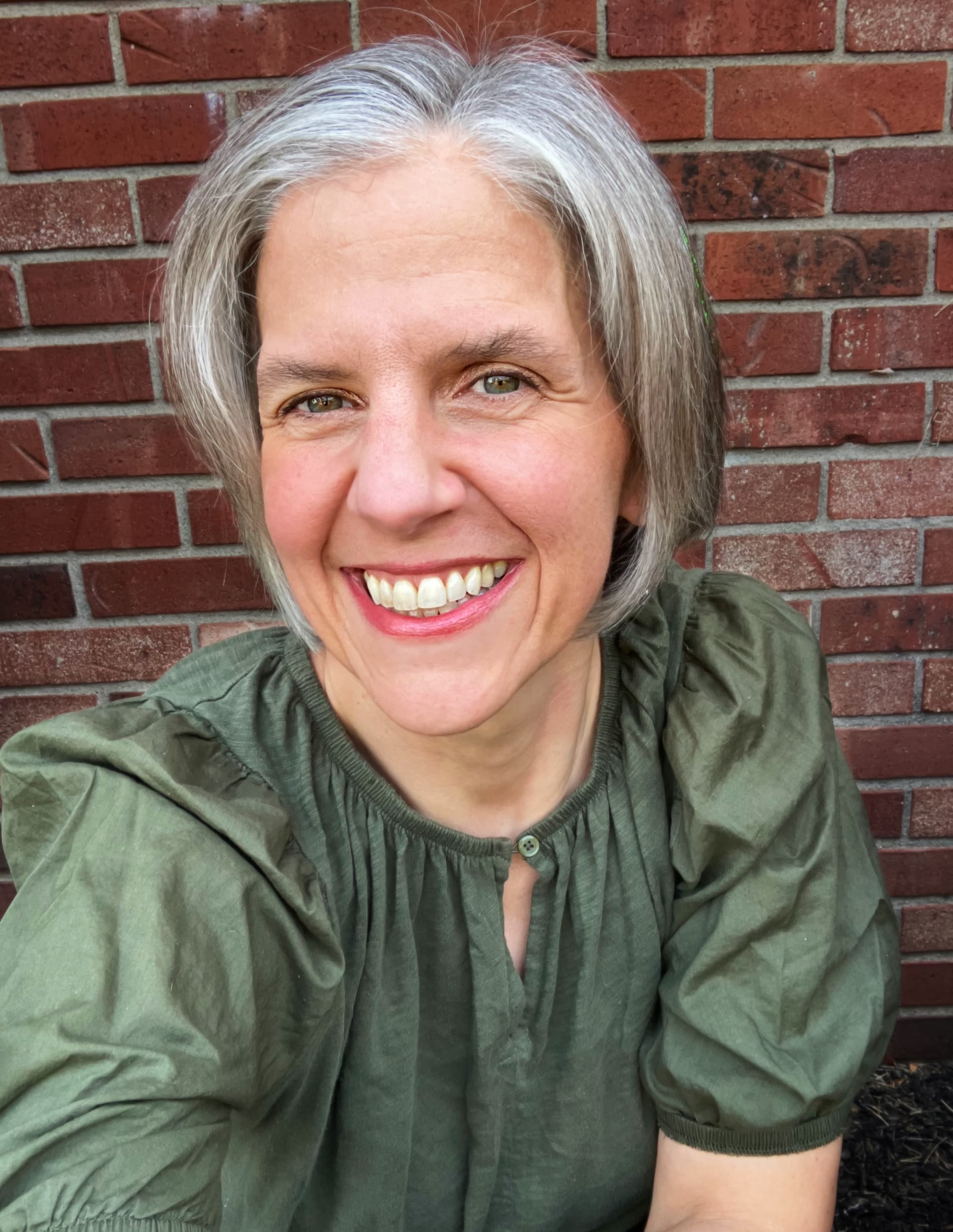 Maria Xavier - Virtual Assistant smiling in front of a brick wall